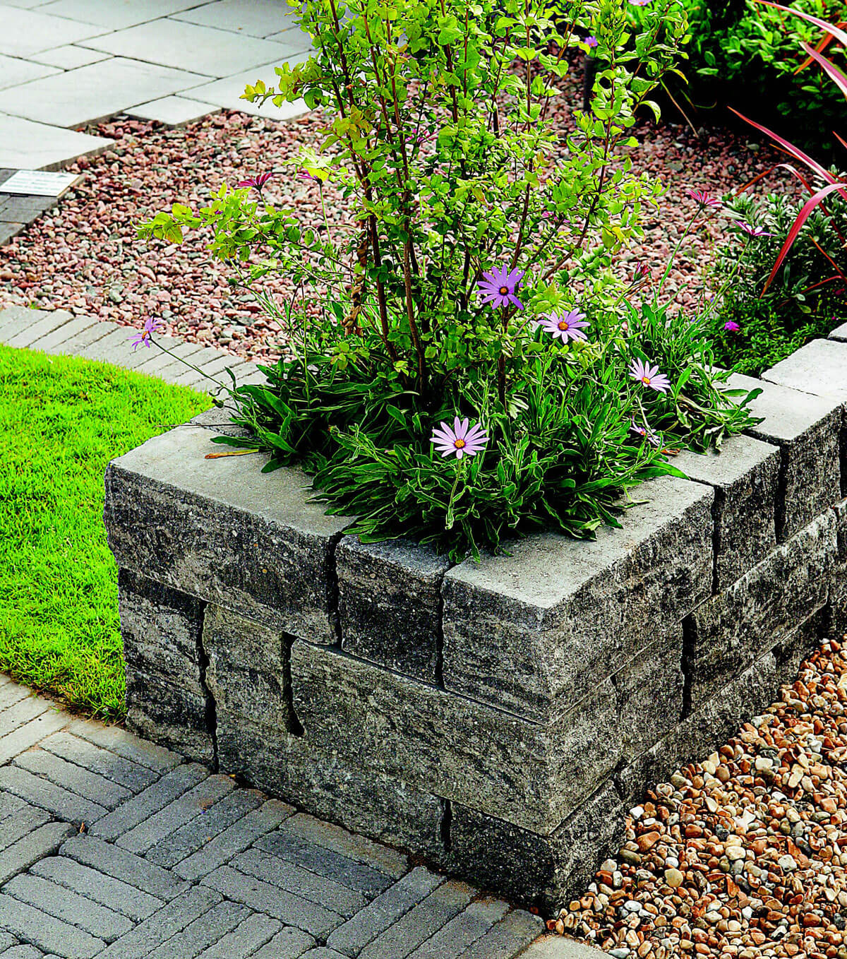 Graue, grobe Betonsteine, die im Vorgarten als Blumenkübel für Str?ucher und Blumen dienen.